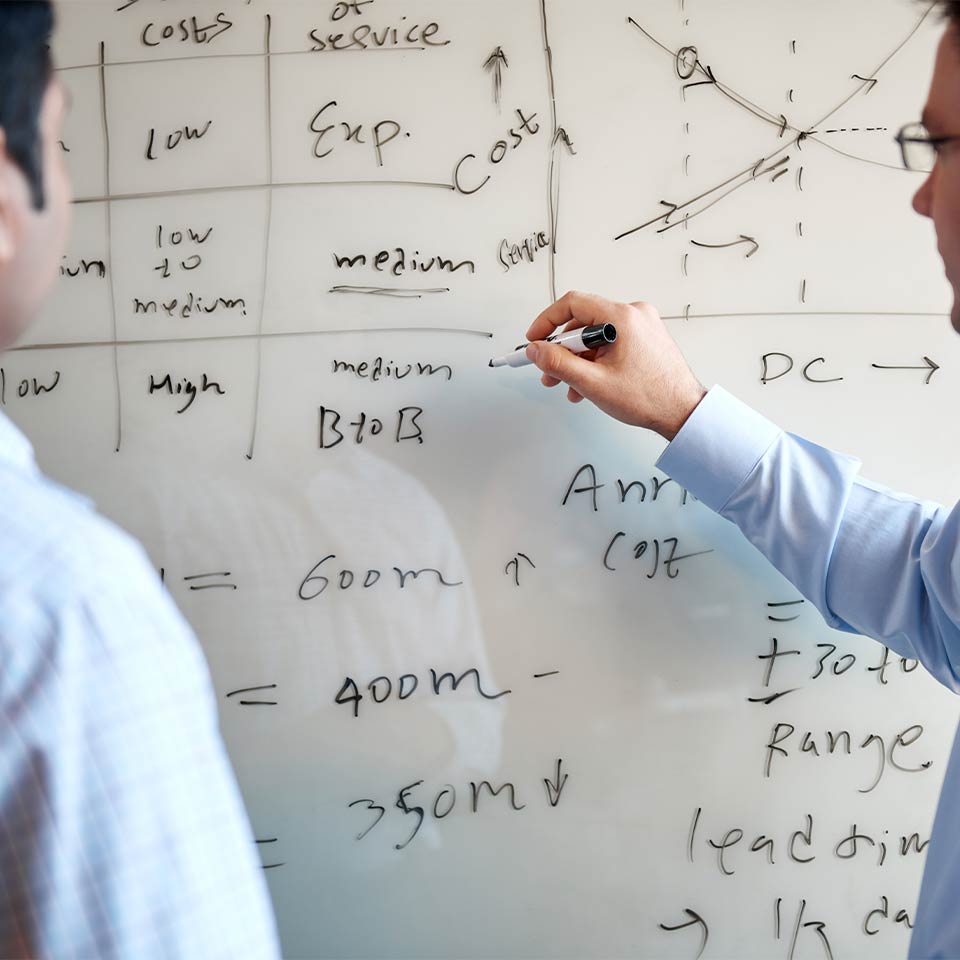 Male co-workers at a whiteboard | Supply chain consulting by C.H. Robinson